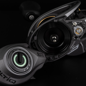 Close-up of the dial side of the VoltiQ fishing reel. The dial side has been removed and placed next to the main unit. The dial is highlighted green to pop in the picture. All set against a black background.