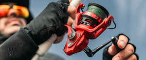 Abu Garcia Revo Rocket Spinning Reel in red held by a person with a blurred blue sky background