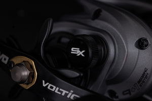 A close up of the handle side of an  Abu Garcia VoltiQ SX fishing reel. Darkened aesthetics on a black background